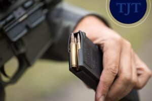 Hand loading brass cartridges into a rifle magazine, representing NJ firearm possession charges